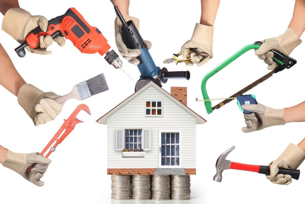A model house sits on stacked coins, surrounded by gloved hands holding tools like a saw, drill, spanner, paintbrush, tape measure, and hammer. - The Handyman Services York Region & Simcoe Region