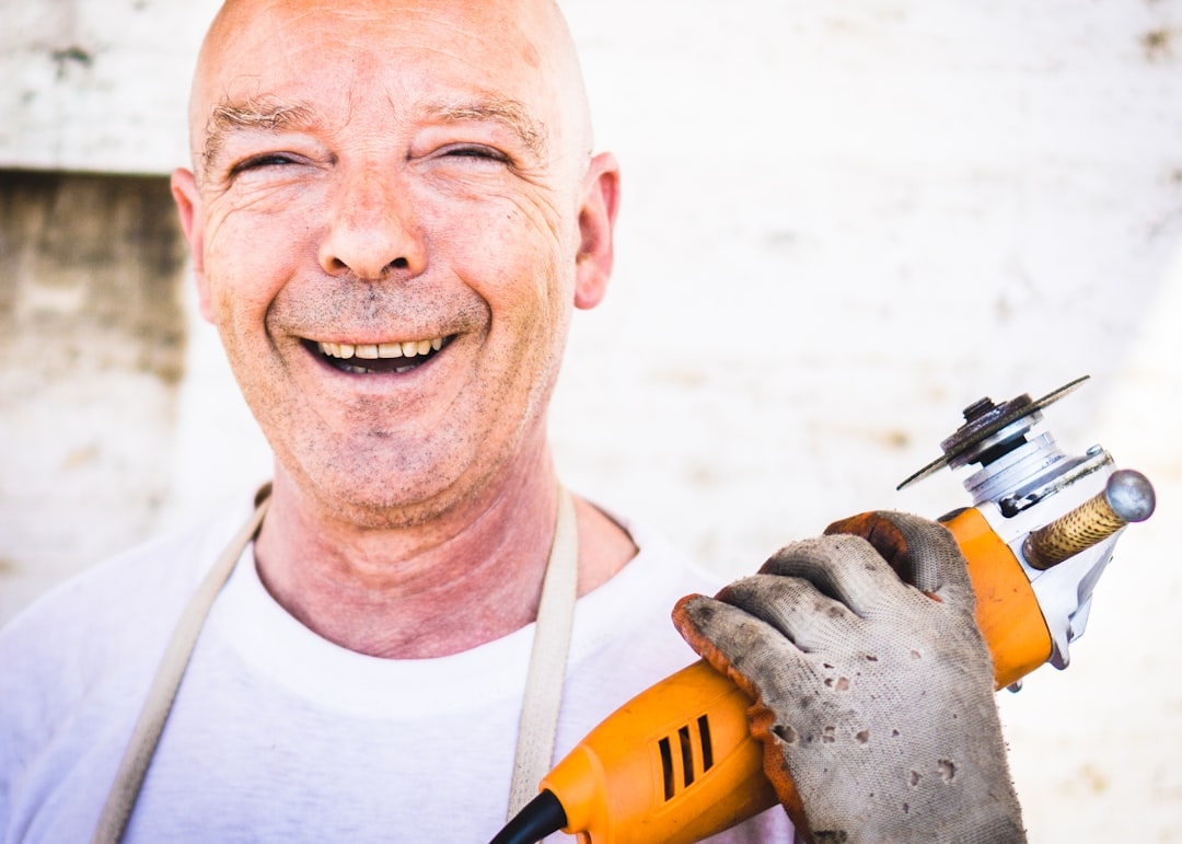 Photo by David Siglin man holding orange angle grinder